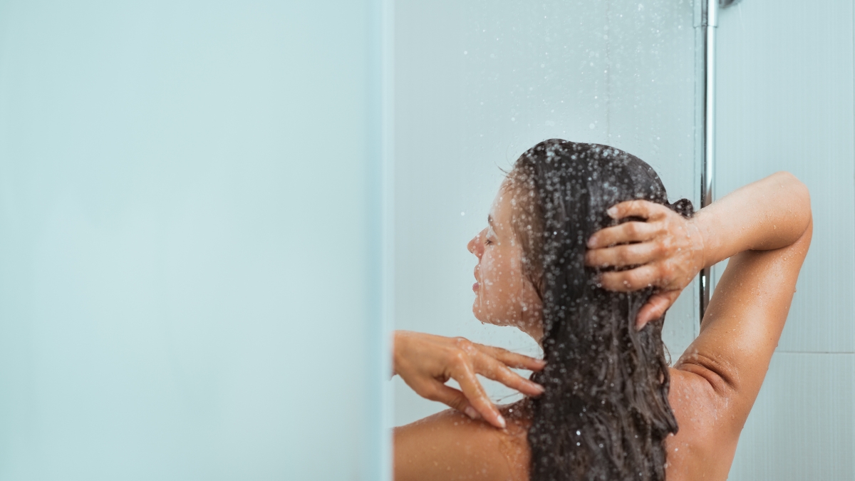 A woman takes a hot shower with steady water flow powered by a tankless water heater.
