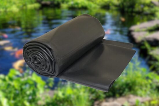 Lifeguard EPDM Pond Liner rolled up in front of a backyard fish pond with rocks and plants.