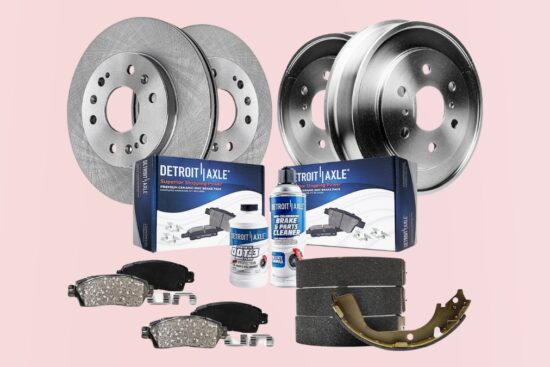 Detroit Axle brake kit with rotors, drums, ceramic brake pads, shoes, cleaner, and brake fluid on a light pink background.