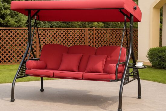 Red 3 in 1 outdoor porch swing with cushions, canopy, pillows, and cup holders on a patio.
