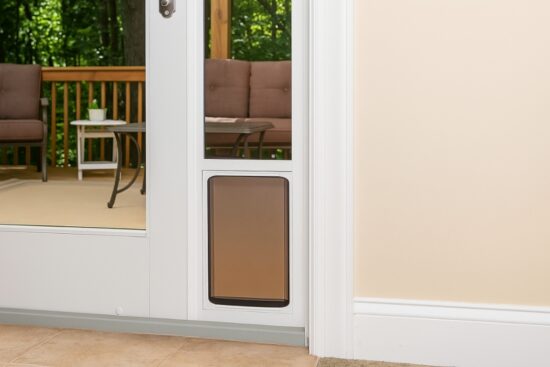 White PetSafe doggy door for sliding glass doors with a tinted flap installed next to a patio.