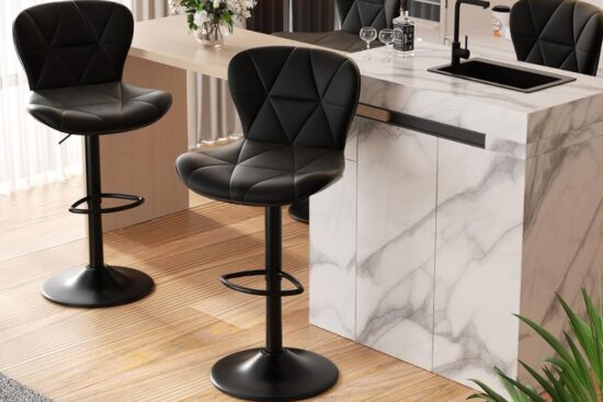 Two modern black bar stools with backs placed by a marble kitchen island in a bright room.