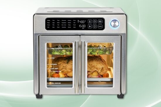 Emeril Lagasse French door air fryer with digital controls cooking rotisserie chicken and vegetables.