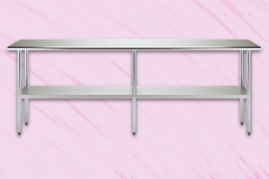 Stainless steel work table with undershelf and six legs on a pink background.