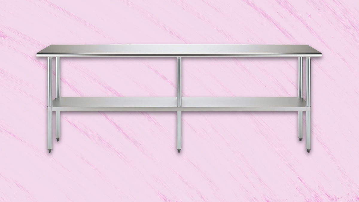 Stainless steel work table with undershelf and six legs on a pink background.