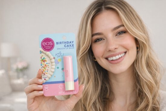 Smiling woman holding EOS Birthday Cake Smooth Lip Balm in pink packaging, showing the birthday cake–inspired lip balm designed for moisturizing and everyday lip care.