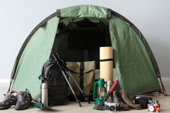 Outdoor adventure gear including backpack, tent, hiking boots, and camping equipment
