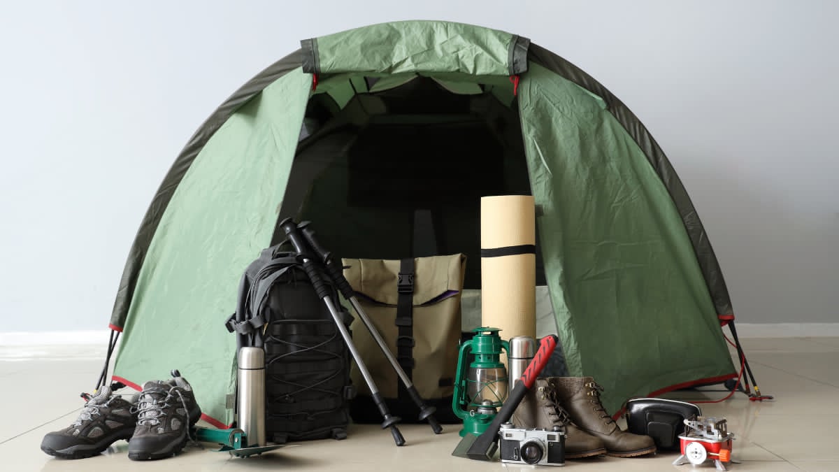 Outdoor adventure gear including backpack, tent, hiking boots, and camping equipment